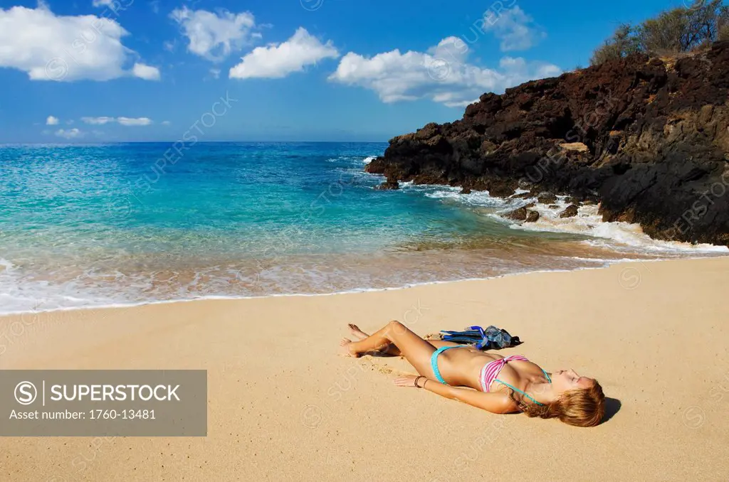 Hawaii, Maui, Makena _ Big Beach, Beautiful woman with snorkel gear relaxing on sandy shore.