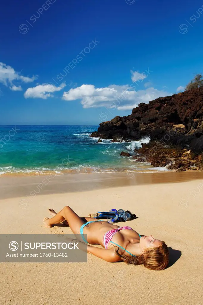 Hawaii, Maui, Makena _ Big Beach, Beautiful woman with snorkel gear relaxing on sandy shore.