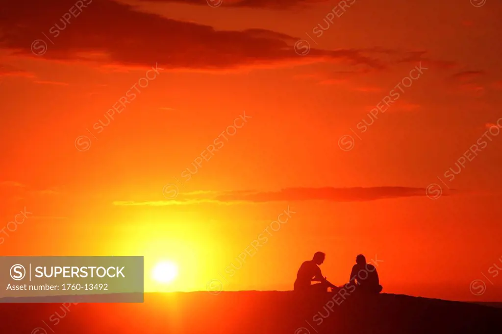 Hawaii, Oahu, Two silhouetted men enjoying the sunset.