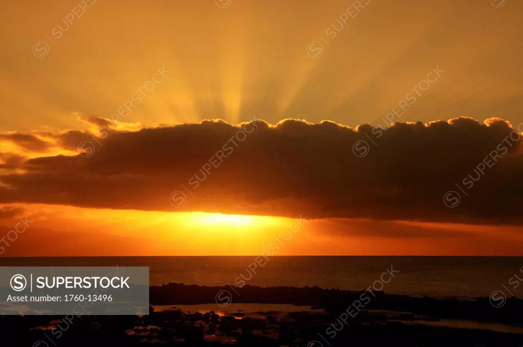 Hawaii, Oahu, North Shore, Dynamic sunset, Sun behind cloud sending sunrays into the sky.