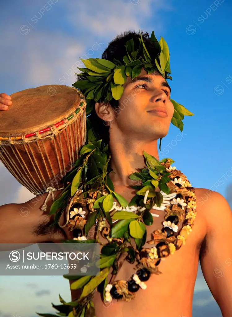 Hawaii, Oahu, Polynesian man with drum along coast, Sunrise light.
