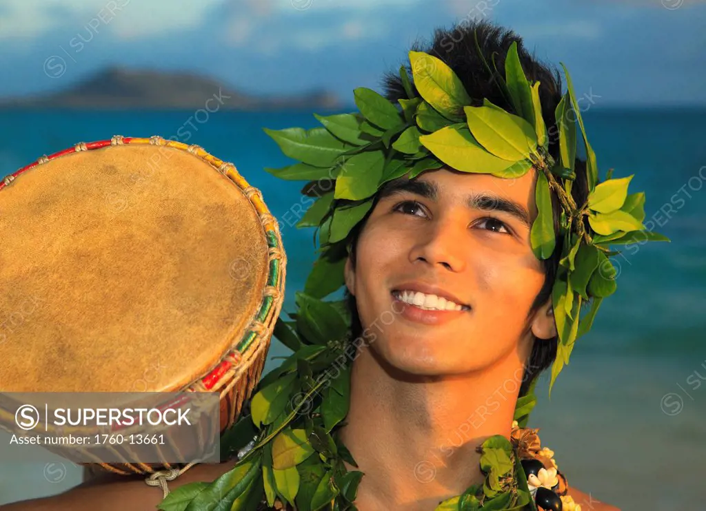 Hawaii, Oahu, Polynesian man with drum along Windward coast, Sunrise light.