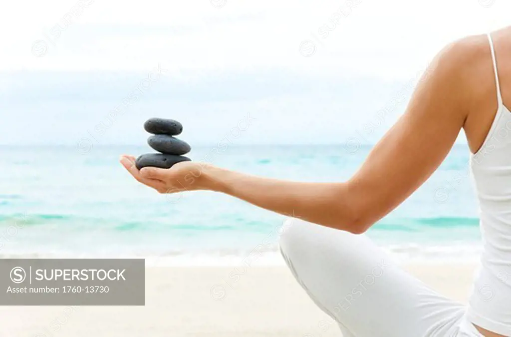 Hawaii, Woman holding stack of stones in hands, Ocean in background.
