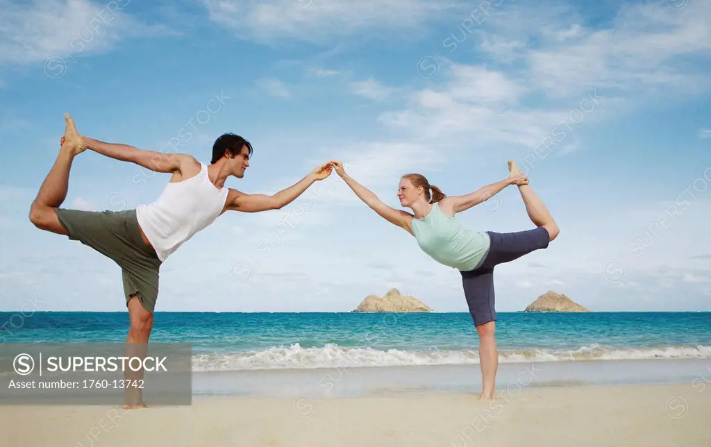 Hawaii, Oahu, Lanikai, Young couple hold a yoga position on the beach.