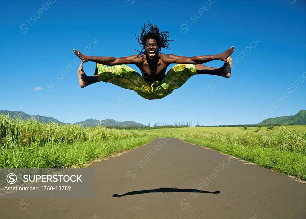 Hawaii, Kauai, Kealia, African dancer leaping into the air on country road.