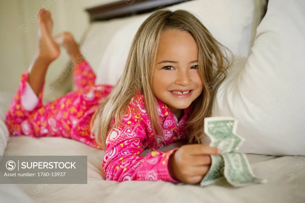 Hawaii, Young girl collecting tooth fairy money from under pillow.