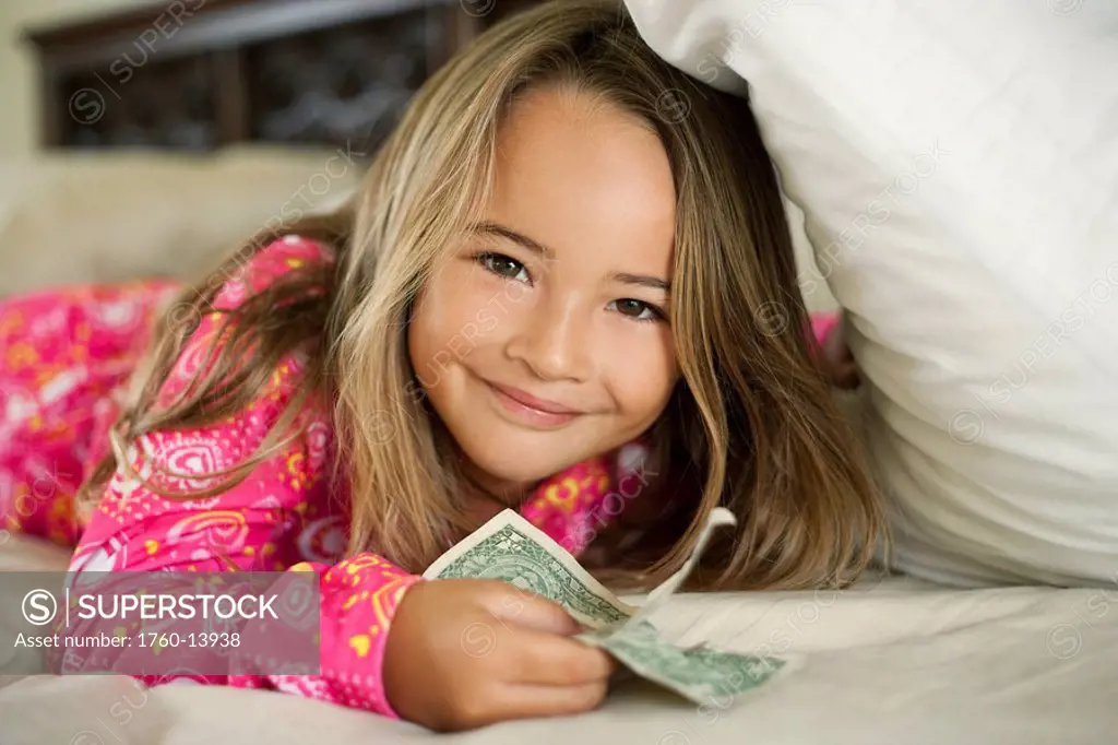Hawaii, Young girl collecting tooth fairy money from under pillow.