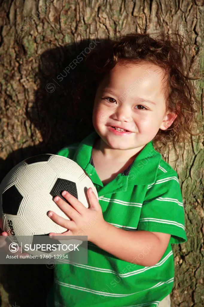 Hawaii, Oahu, Waikiki, Young boy poses for camera with his soccerball.