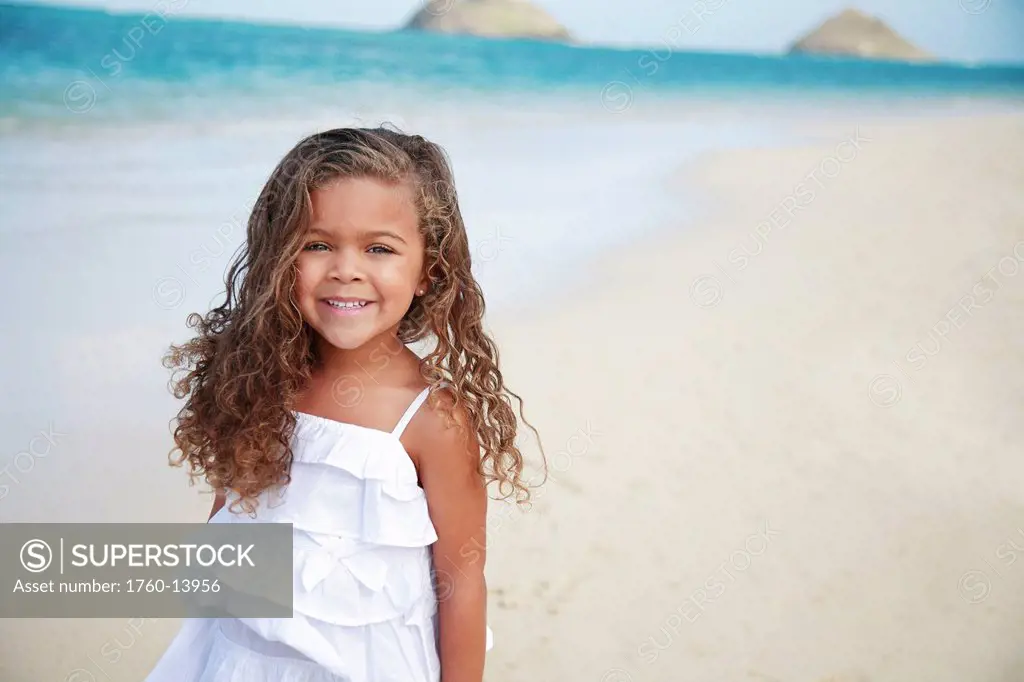 Hawaii, Oahu, Lanikai, Young girl smiles at camera on beach.
