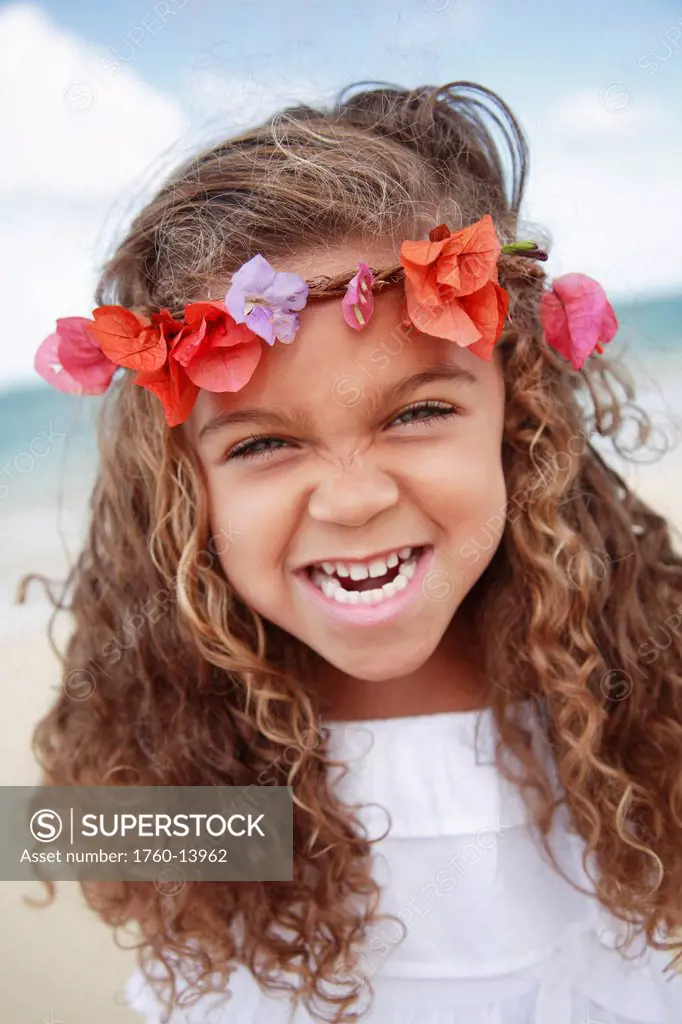 Hawaii, Oahu, Lanikai, Young girl wearing flower headband makes funny face at beach.