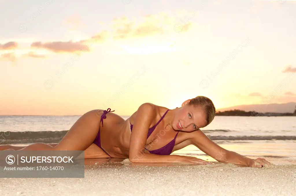 Hawaii, Oahu, Blond woman lounging on beach, Sunset light.