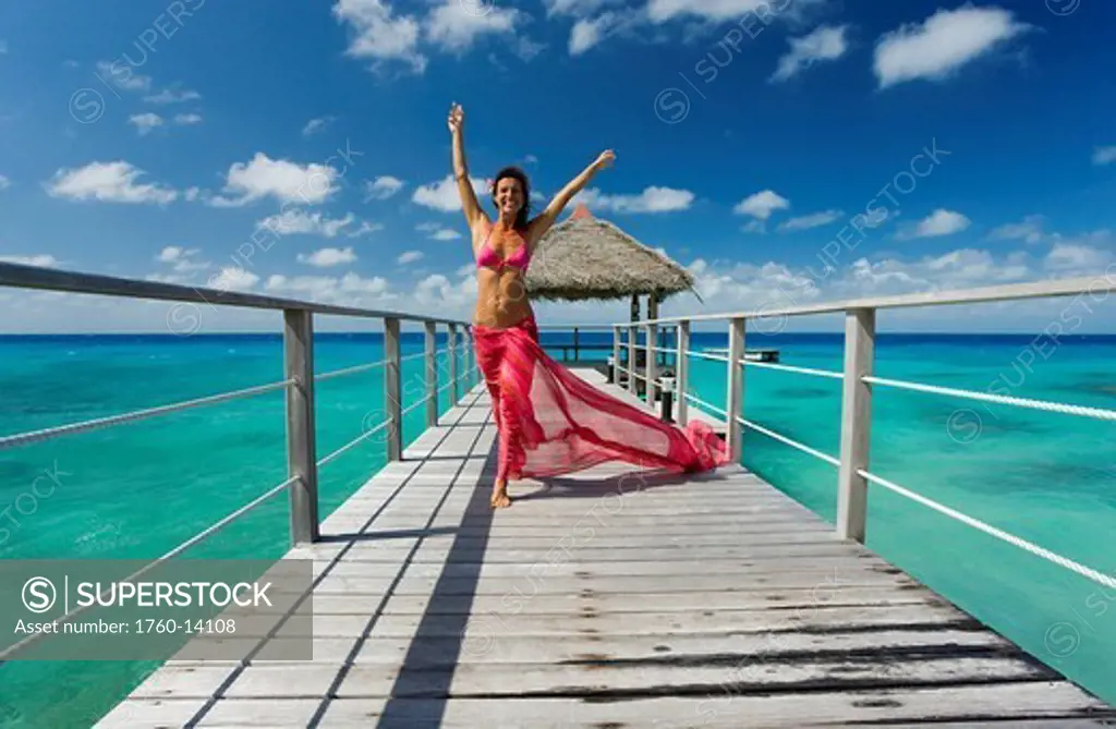 French Polynesia, Tuamotu Islands, Rangiroa Atoll, Woman walking on ocean pier wearing pink pareo.