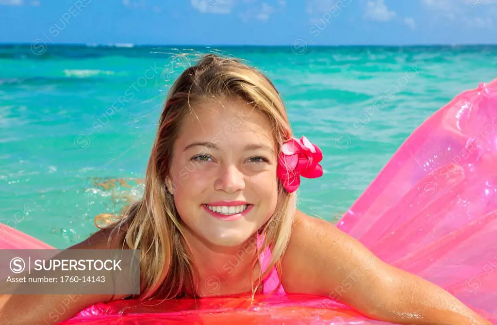 Hawaii, Teenage girl in ocean with inflatable.
