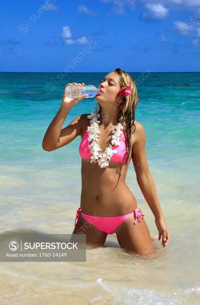 Hawaii, Teenage girl on beach with bottle of water.