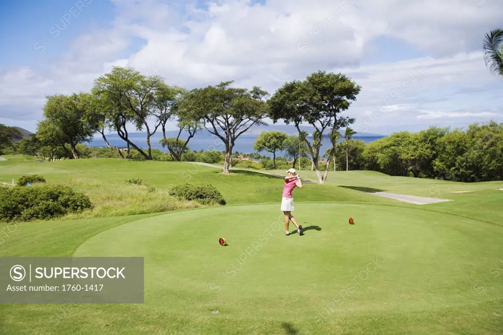 Hawaii, Maui, Wailea Gold Golf Course, Female golfer swinging golf club, view from side.