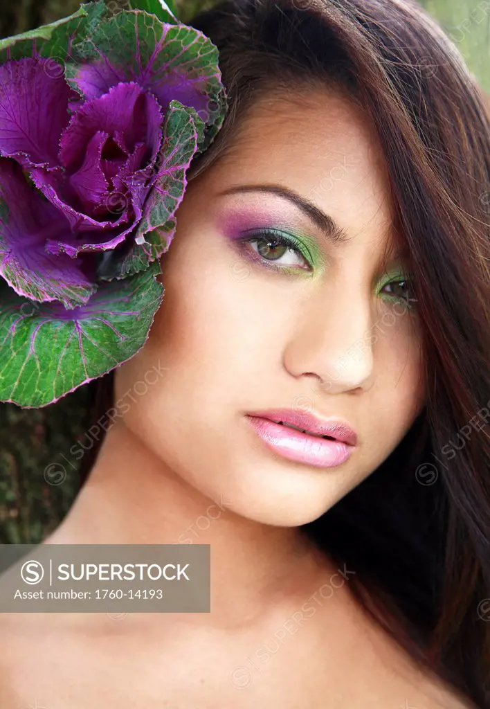 Hawaii, Oahu, Fashion model poses with plant behind ear.