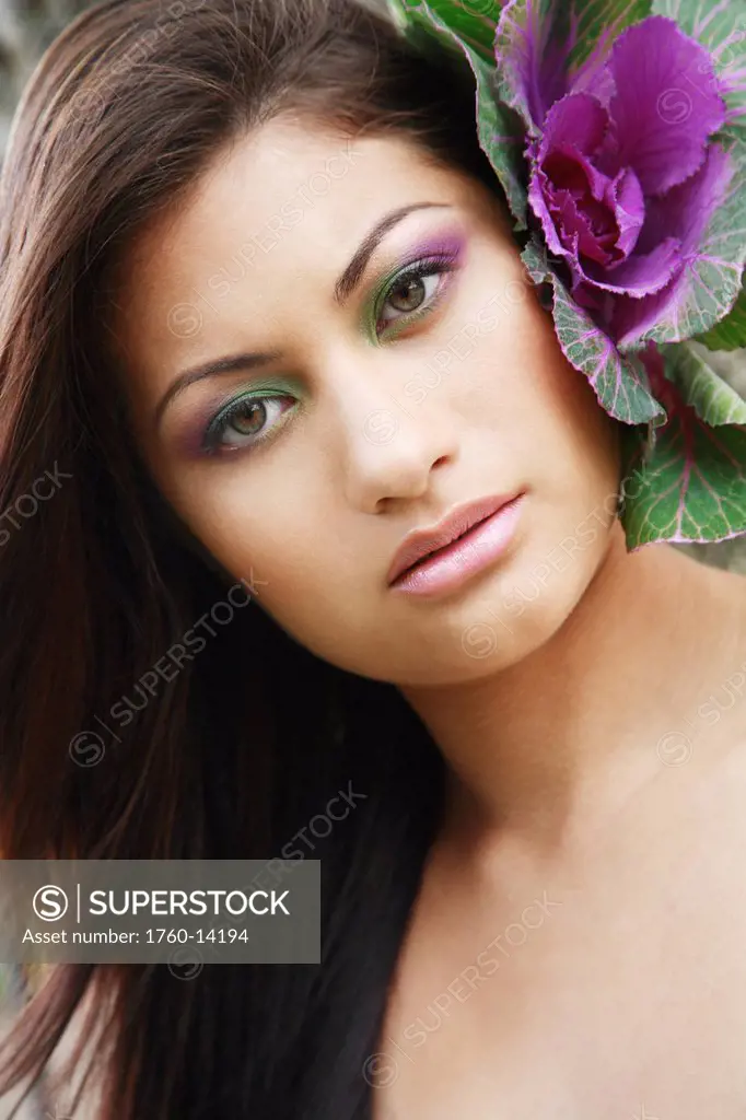 Hawaii, Oahu, Fashion model poses with plant behind ear.