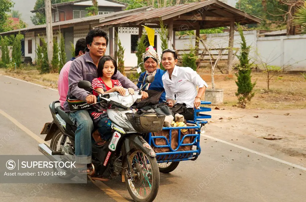 Thailand, Chiang Mai Province, Family riding motorcycle and sidecar through village along Mae Tang River.