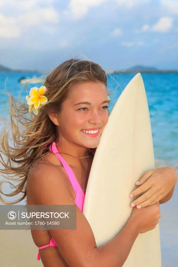 Hawaii, Oahu, Lanikai, Blond surfer girl with surfboard along beach.