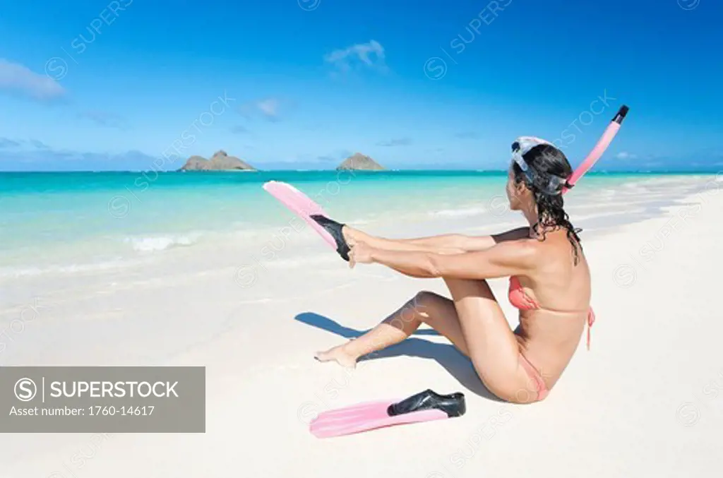 Hawaii, Oahu, Lanikai Beach, Woman putting on snorkel gear at ocean´s edge.