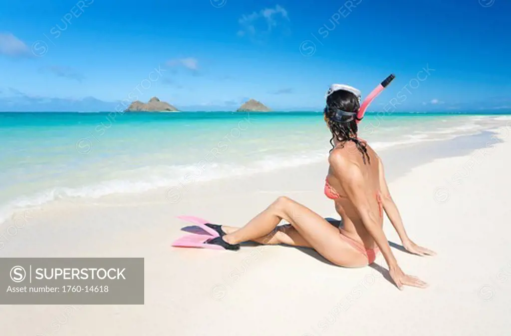 Hawaii, Oahu, Lanikai Beach, Woman sitting on beach wearing snorkel gear.