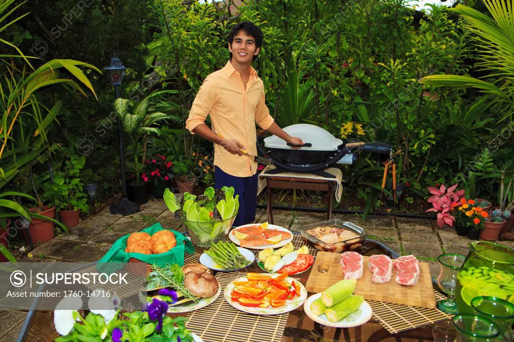 Hawaii, Young man preparing Outdoor barbecue feast in Hawaii garden.