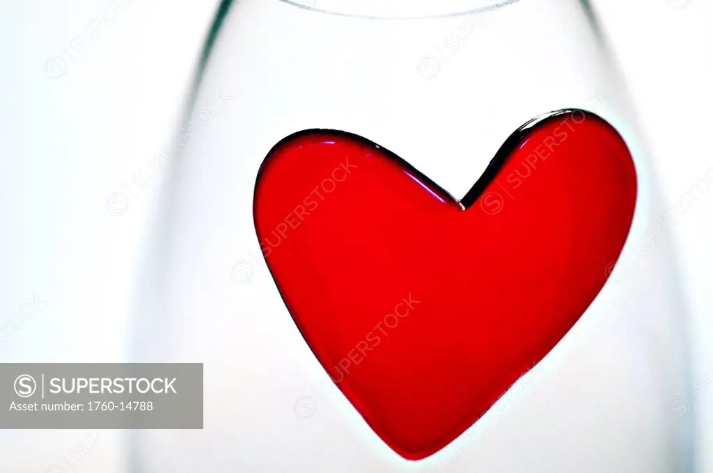 A heart shaped decoration is placed on wine glass for Valentines Day, shot in studio.