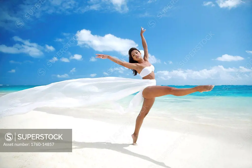 Hawaii, Oahu, Lanikai Beach, Beautiful female ballet dancer on beach wearing white flowing fabric.