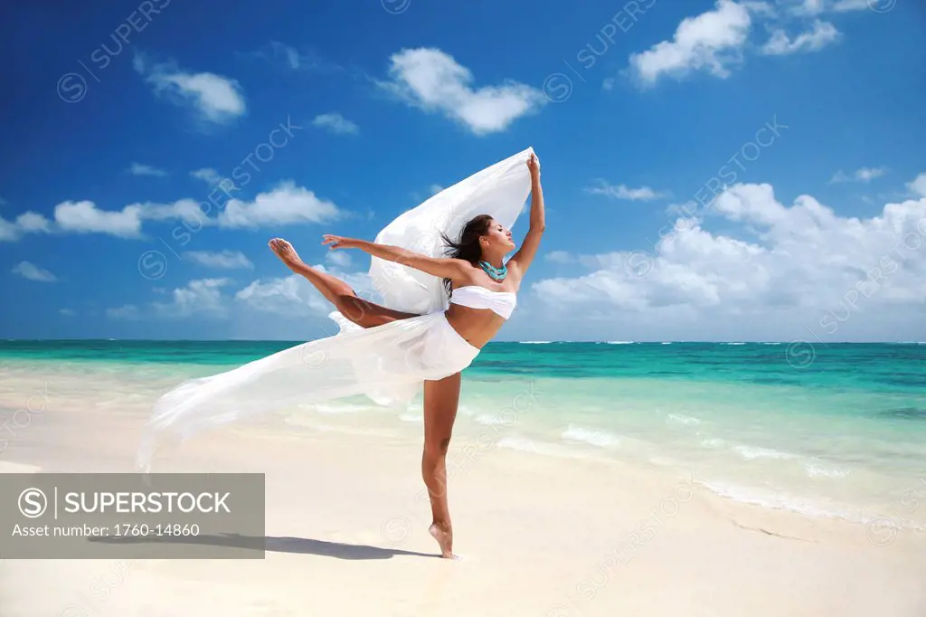 Hawaii, Oahu, Lanikai Beach, Beautiful female ballet dancer on beach with white flowing fabric.