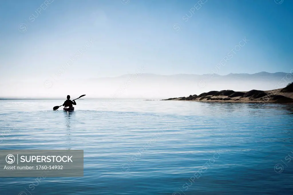 California, Morro Bay State Park, Woman kayaking in ocean, silhouette.