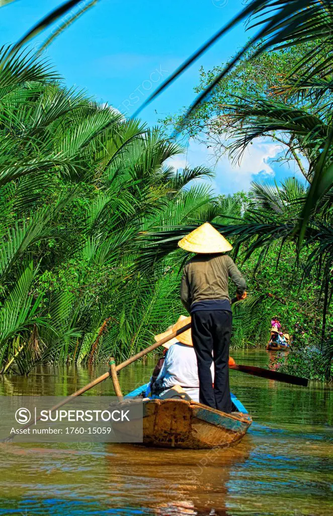 South East Asia, Vietnam, Saigon, Mekong Delta River, Women paddle down a muddy river.