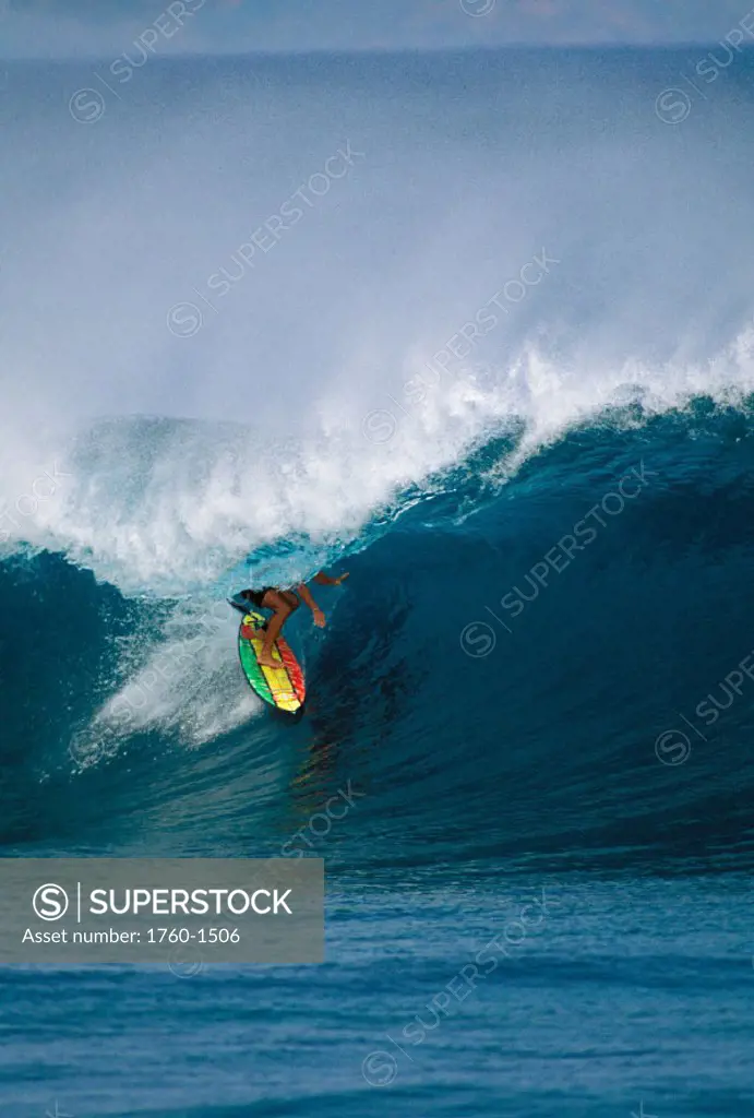 Hawaii, Oahu, North Shore, Pipeline, Surfer rides tube under curl on Rasta colored board