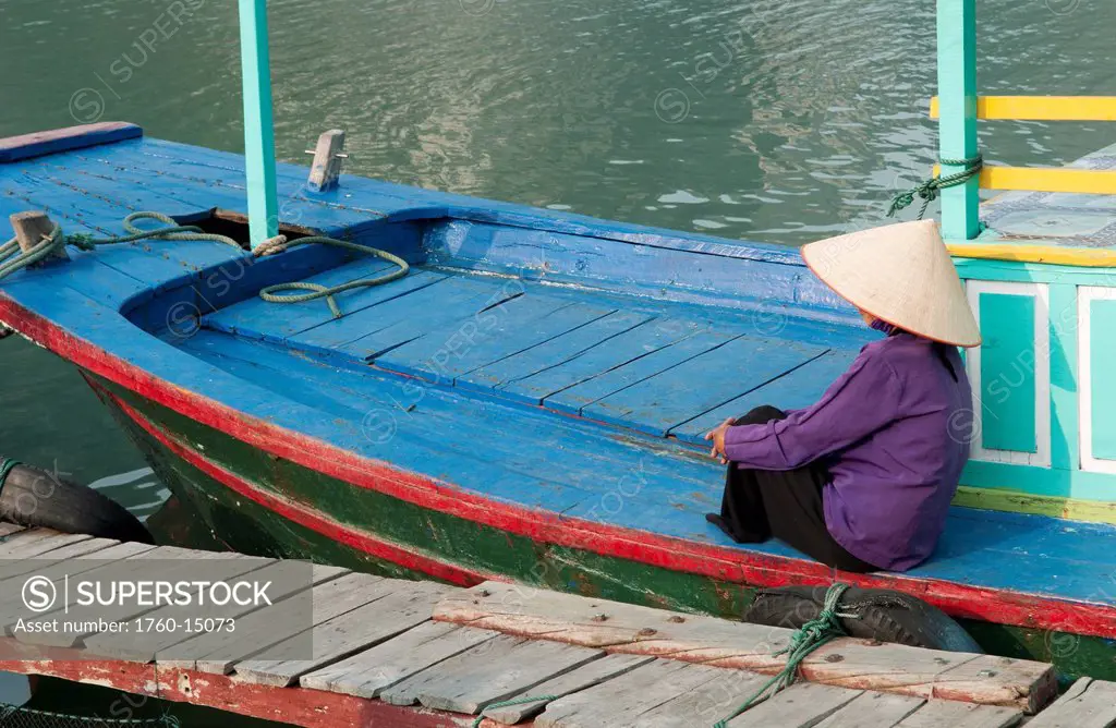 South East Asia, Vietnam, Ha Long Bay, Portrait of a Vietnamese woman sitting on docked fishing boat, side view.