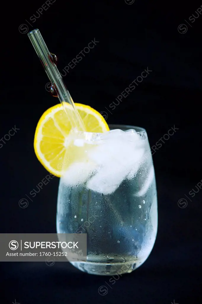 Glass of ice water with lemon and a glass straw.