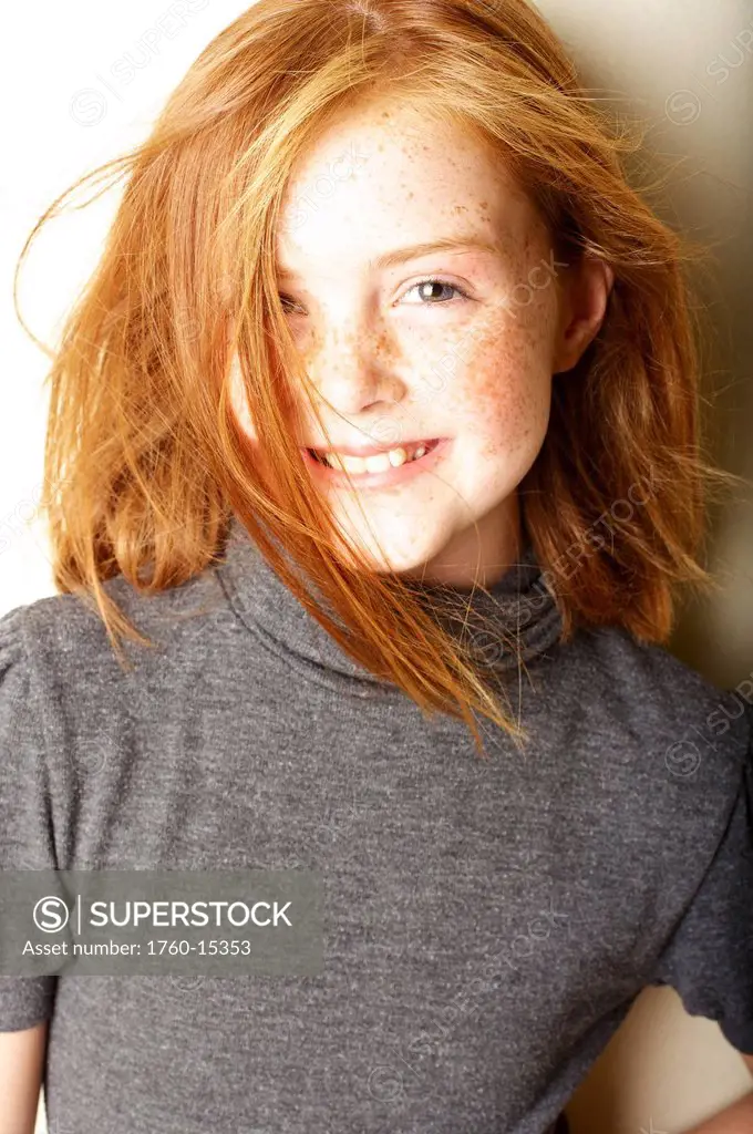 Young girl with red hair and freckles smiles for a portrait.