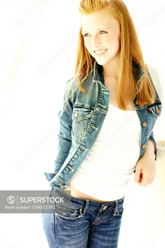 Teenage girl with red hair and freckles models her denim fashion in the studio.