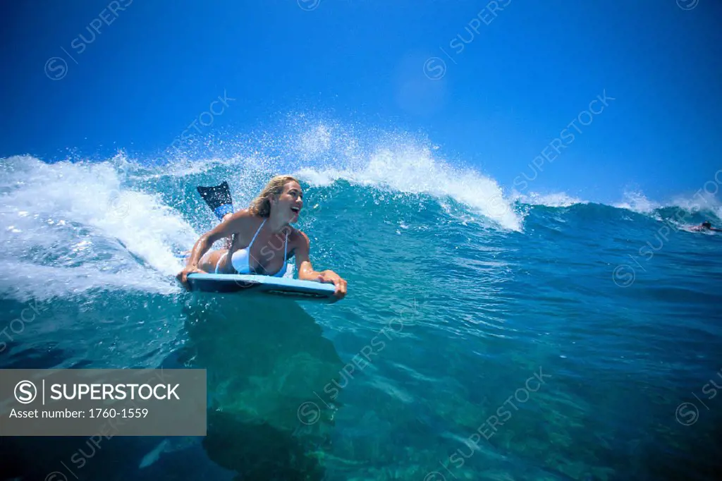 Woman body boarder in bikini rides wave over reef C1405