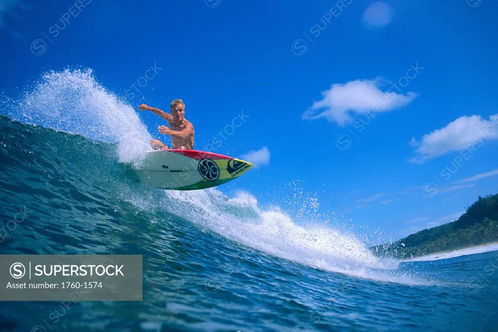 Hawaii, Noah Budroe surfing, cuts over wave, looks at camera, blue skies C1407
