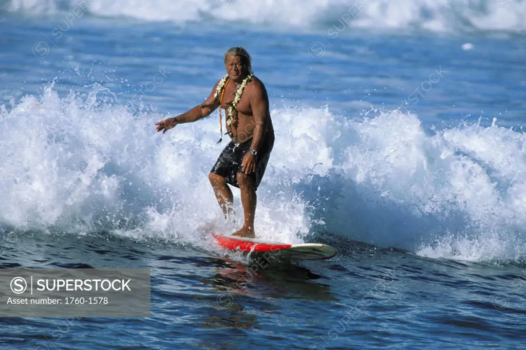 Legendary beachboy, Buffalo K, Surfing wave on longboard wearing lei