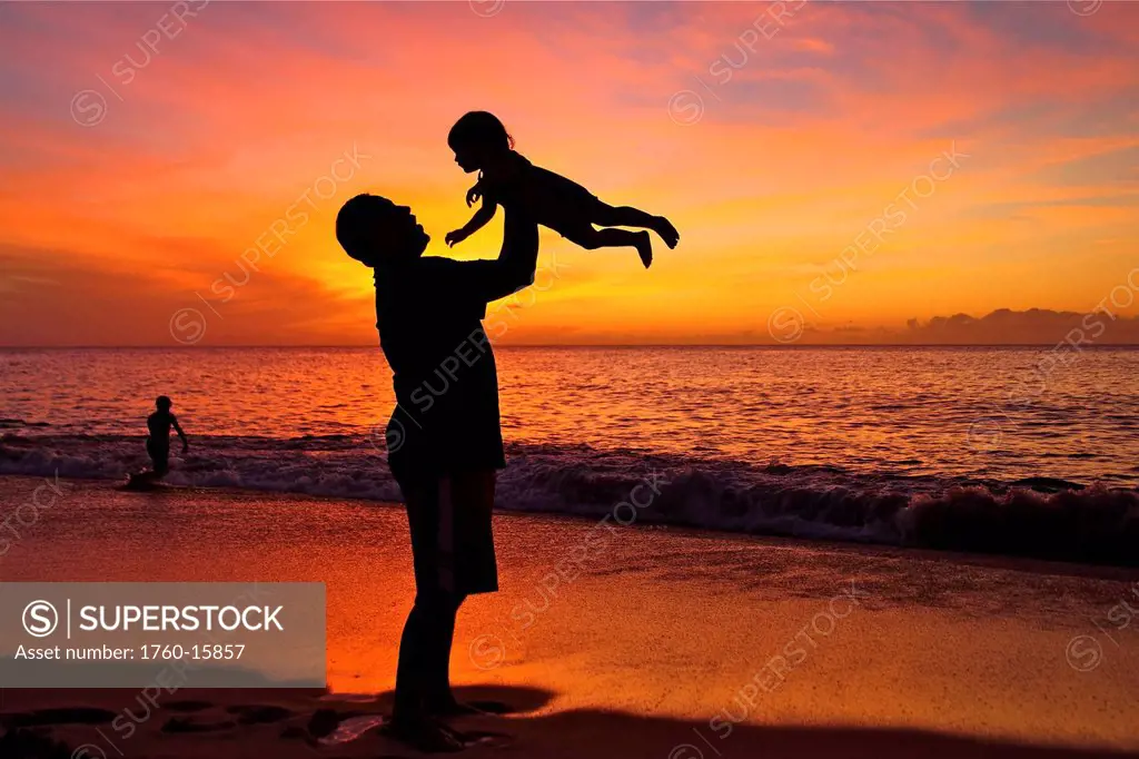Silhouette of father and child on the beach