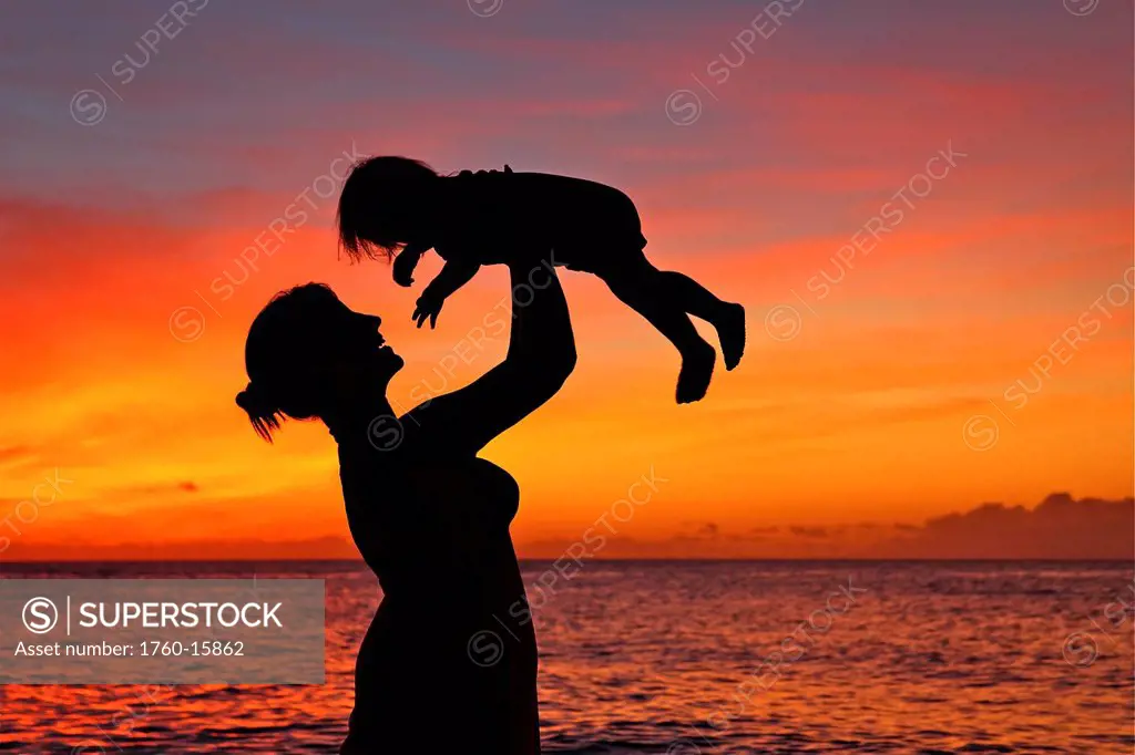 Silhouette of a mother and child on the beach.