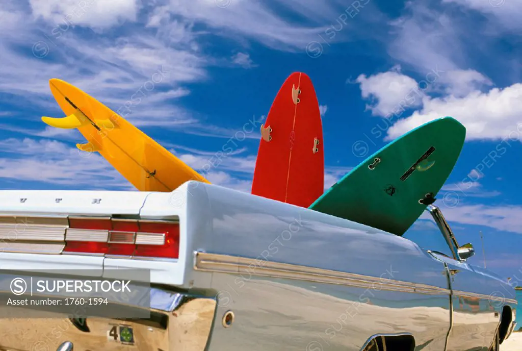 Colorful surfboards in vintage Plymouth Fury, puffy clouds in background