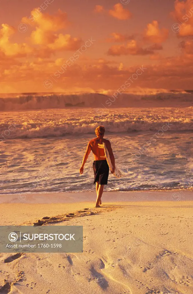 Surfer walking into the water from the beach