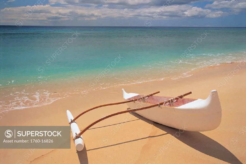 White outrigger canoe on shoreline with shadow, calm turquoise water