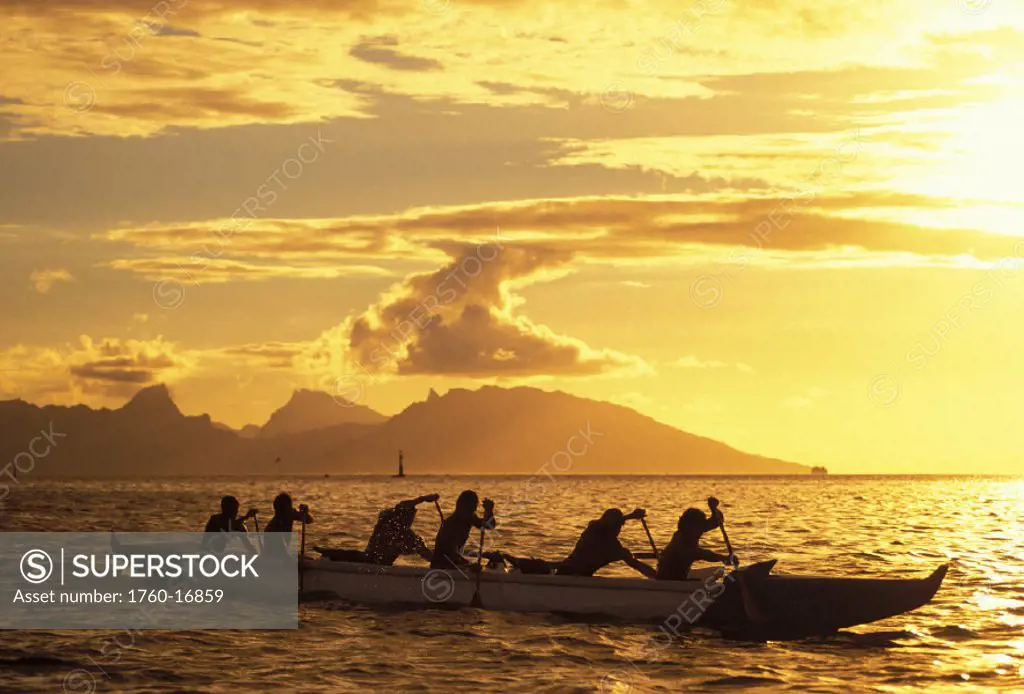 French Polynesia, Tahiti, Papaeete, men in outrigger canoe paddling at sunset, golden sunlight and reflections on ocean