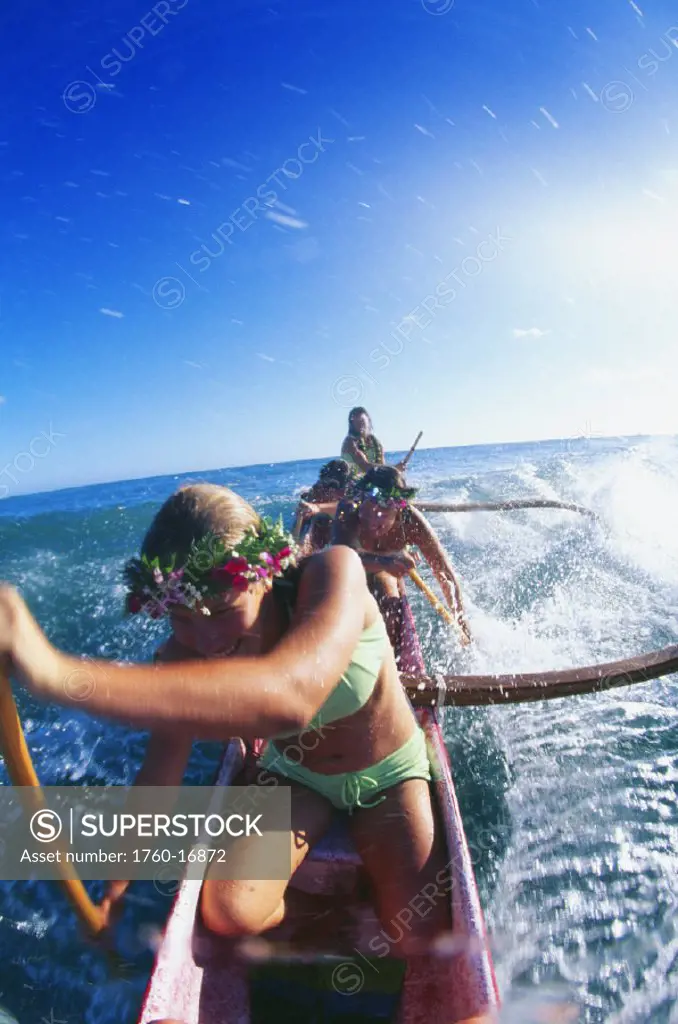 Closeup front view of girls outrigger canoe surfing, afternoon, bright blue sky ocean teenager