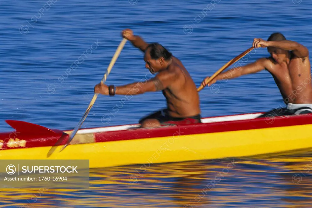 Closeup side view of men in outrigger canoe reaching, about to stroke paddling Hawaii Maui action