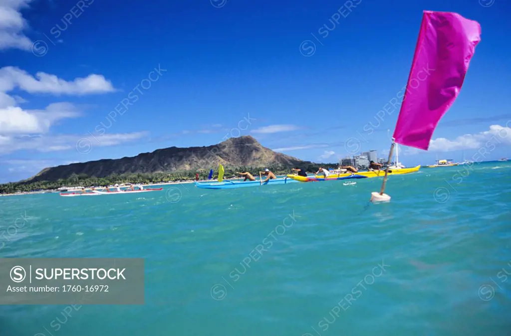 Hawaii, Oahu, Waikiki, Outrigger canoes pass by flags in a race, Diamond Head in background. NO MODEL RELEASE