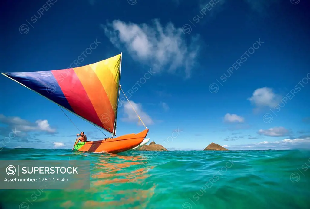 Hawaii, Oahu, Lanikai, Man in colorful sailing canoe.