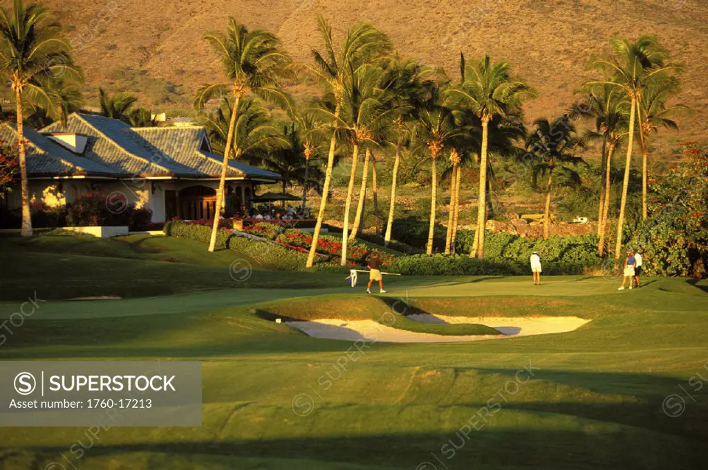 Hawaii, Lanai, The Challenge at Manele golfers at 18th hole with clubhouse background, afternoon shadows and light